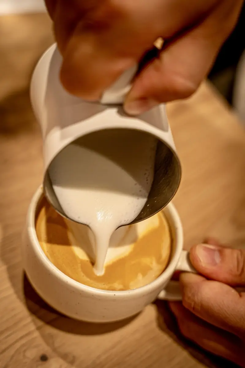 Milchschaum wird als Latte Art in eine Tasse gegossen